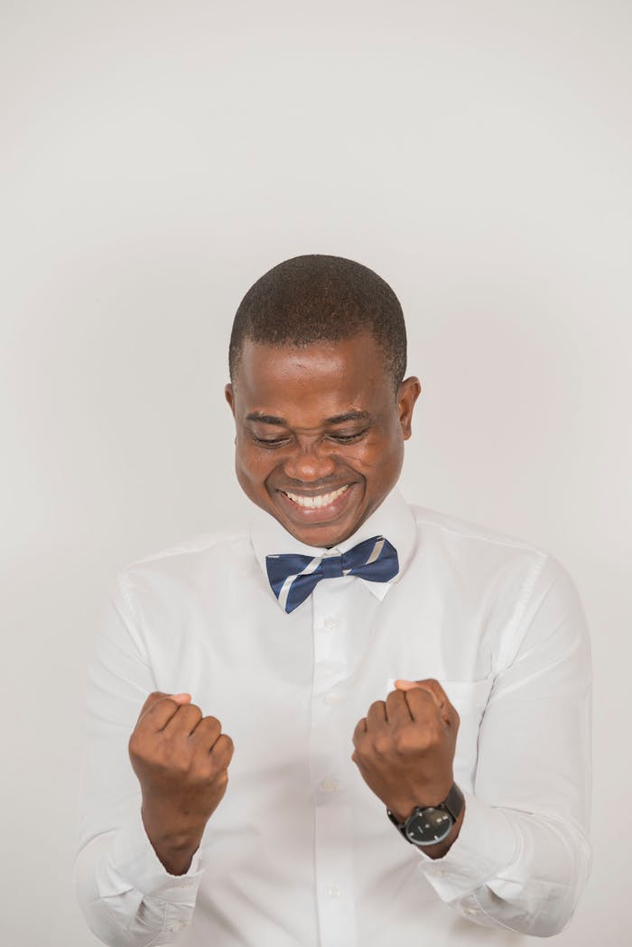 A cheerful man celebrates success, smiling with joy in a stylish outfit.